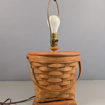 Sale Photo Thumbnail #117: Vintage woven splint basket table lamp with a wooden base, top lid, dual swing handles, and a brass harp.