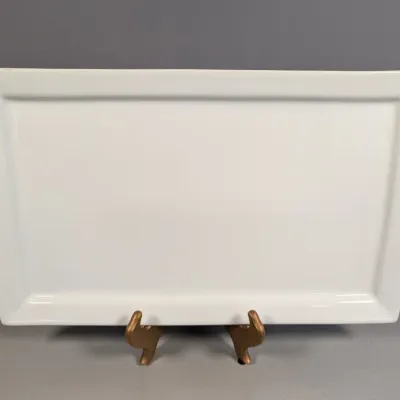 Sale Photo Thumbnail #148: Large rectangular white ceramic serving platter displayed on a gold-toned stand.