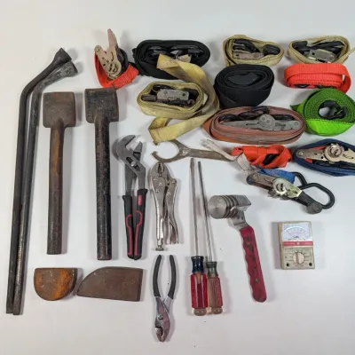 Sale Photo Thumbnail #65: Assorted vintage hand tools and hardware, including hammers, pry bars, locking pliers, screwdrivers, a multimeter, and several ratchet straps.