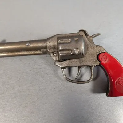 Sale Photo Thumbnail #316: Vintage Kilgore Ranger cast metal toy cap gun featuring a red plastic grip, mid-20th century.
