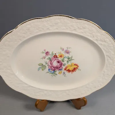 Sale Photo Thumbnail #178: Vintage oval porcelain serving platter featuring a central floral bouquet pattern, embossed rim detail, and gold gilded edge.
