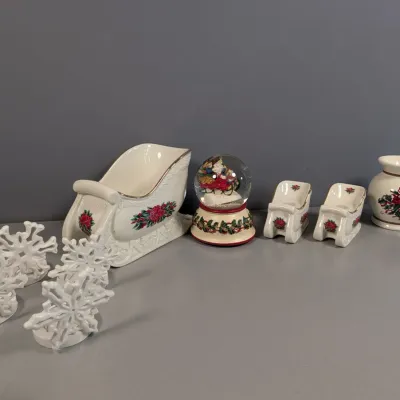 Sale Photo Thumbnail #141: Collection of holiday porcelain decor, including a sleigh candy dish, matching salt and pepper shakers, a vase with poinsettia details, a musical snow globe, and four snowflake place card holders.