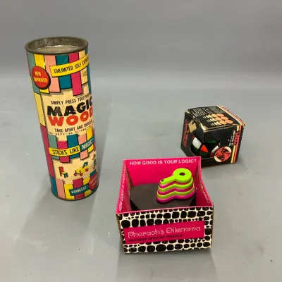 Sale Photo Thumbnail #275: Collection of three vintage mid-century puzzles and toys, including a Magic Wood canister, Pharaoh's Dilemma logic puzzle in original box, and a boxed Magic Ball puzzle.