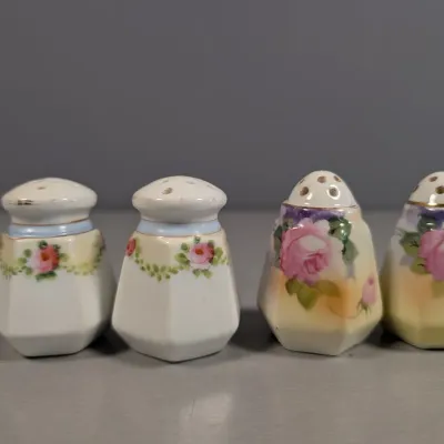 Sale Photo Thumbnail #134: Two sets of vintage hand-painted porcelain salt and pepper shakers featuring floral designs and gold accent trim.