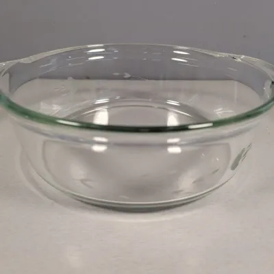 Sale Photo Thumbnail #135: Round clear glass baking dish or casserole bowl with side tab handles and subtle etched floral details, shown in good vintage condition.