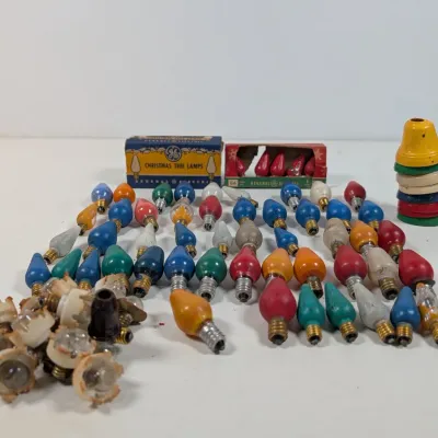 Sale Photo Thumbnail #231: Collection of vintage General Electric C-6 Christmas tree light bulbs, original packaging boxes, light sockets, and metal lamp reflectors.