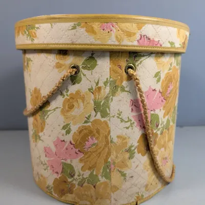 Sale Photo Thumbnail #180: Vintage quilted floral sewing basket featuring yellow and pink roses with braided rope handles and a matching lid.