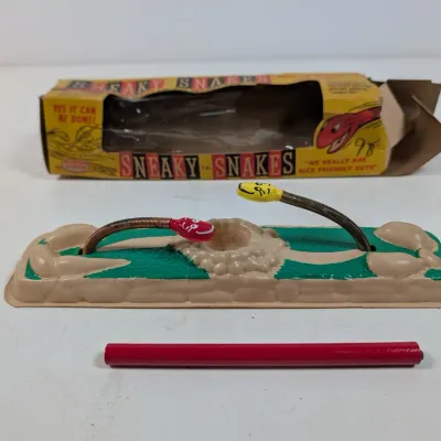 Sale Photo Thumbnail #424: Vintage Sneaky Snakes skill game by Empire, featuring flexible metal snakes on a plastic base with original worn packaging.