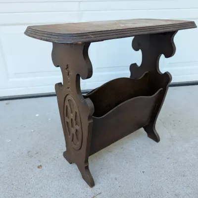 Sale Photo Thumbnail #44: Vintage dark wood magazine rack end table with carved side details and visible surface wear.