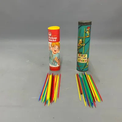 Sale Photo Thumbnail #398: Two vintage pick-up sticks games, including a Pressman Plastic Pickup Sticks set and a Steven Pixie Pick-Up Stix set with original cardboard containers.
