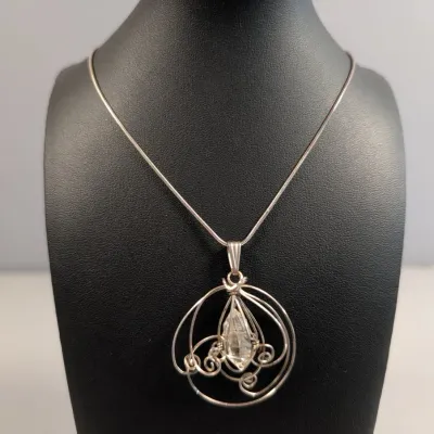 Sale Photo Thumbnail #435: Handcrafted wire-wrapped clear quartz pendant necklace on a delicate silver snake chain, displayed on a black jewelry bust.