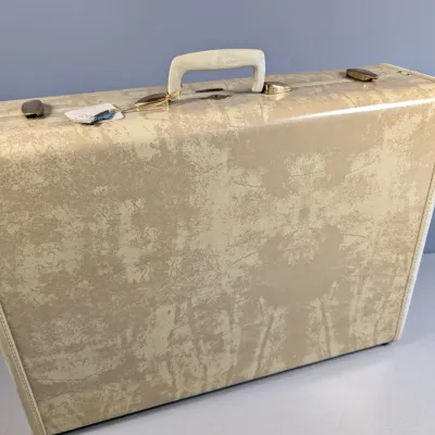 Sale Photo Thumbnail #170: Vintage hard-shell suitcase with a beige mottled pattern, off-white trim, and brass-tone latches, circa 1960s.