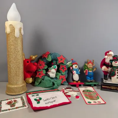 Sale Photo Thumbnail #152: Assortment of Christmas holiday decorations including a large glittery gold candle lamp, Santa Claus and snowman figures, stocking holders, and an embroidered Santa envelope.