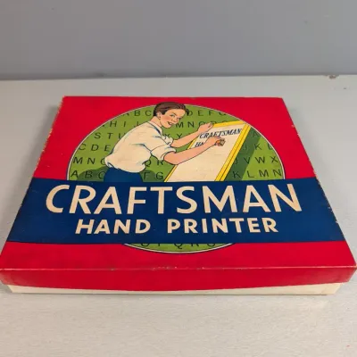 Sale Photo Thumbnail #444: Vintage Craftsman Hand Printer set in original red and blue illustrated cardboard box showing light edge wear.