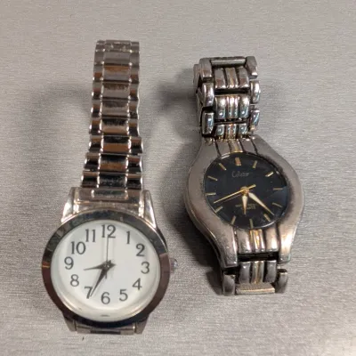 Sale Photo Thumbnail #146: Pair of vintage quartz wristwatches with metallic link bracelets, including a silver-tone watch with a white dial and a Collezio watch with a black face.