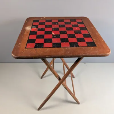 Sale Photo Thumbnail #158: Vintage wooden folding game table featuring a stenciled red and black checkerboard top, showing visible surface wear and distressing.