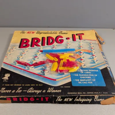 Sale Photo Thumbnail #183: Vintage 1960 Bridg-It board game by Hassenfeld Bros. (Hasbro), featuring red and yellow plastic game pieces in a worn original box.