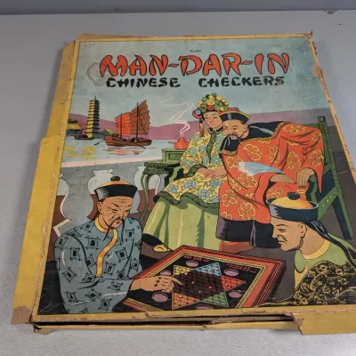 Sale Photo Thumbnail #186: Vintage Man-Dar-In Chinese Checkers board game in its original illustrated box, showing heavy wear and tape repairs around the edges.