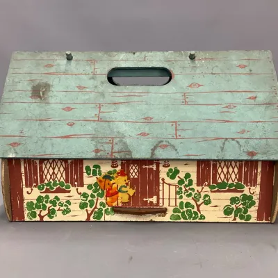 Sale Photo Thumbnail #212: Vintage lithographed wooden toy cottage box with a carrying handle, featuring cottage and teddy bear graphics with visible surface wear.