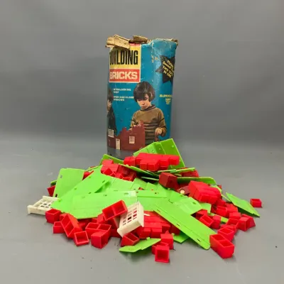 Sale Photo Thumbnail #301: Vintage plastic Building Bricks construction set with a large pile of red, lime green, and white pieces alongside its original worn cylindrical storage container.