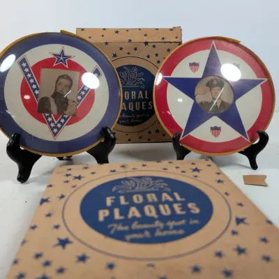 Sale Photo Thumbnail #80: Pair of World War II-era patriotic convex glass picture frames featuring military portraits, displayed with their original star-patterned Floral Plaques box.