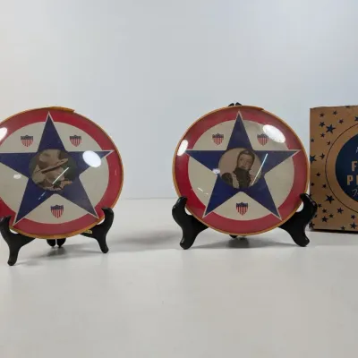 Sale Photo Thumbnail #71: Pair of vintage World War II era patriotic glass picture plaques with red, white, and blue star designs, displayed on stands with an original Floral Plaques box.