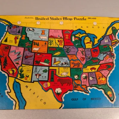 Sale Photo Thumbnail #188: Vintage Built-Rite inlaid cardboard United States map puzzle featuring colorful state illustrations and state nicknames.