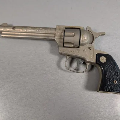 Sale Photo Thumbnail #204: Vintage Nichols Stallion 38 die-cast toy cap gun revolver featuring embossed scrollwork and black faux-stag grip panels.