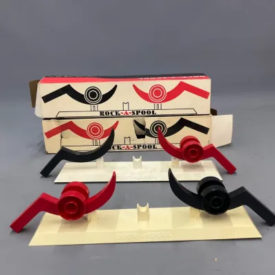 Sale Photo Thumbnail #394: Vintage mid-century Rock-A-Spool game featuring plastic playing bases, red and black spools, and original printed packaging.
