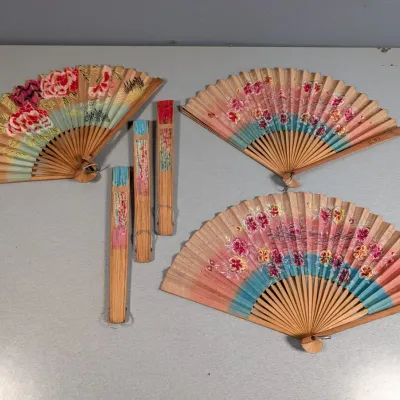 Sale Photo Thumbnail #360: Collection of six vintage wooden folding hand fans with hand-painted floral designs on paper leaves.