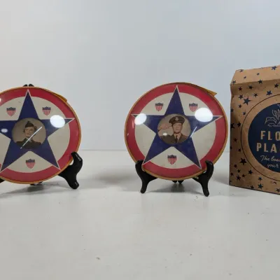 Sale Photo Thumbnail #73: Pair of WWII-era patriotic circular photo frames featuring service member portraits, displayed on mini stands with a vintage box.