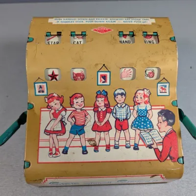 Sale Photo Thumbnail #192: Vintage Wolverine tin lithograph child's spelling toy game featuring illustrated children and mechanical push levers.