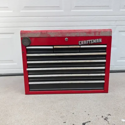 Sale Photo Thumbnail #86: Vintage red Craftsman multi-drawer rolling or top tool chest featuring silver-tone trim handles and heavy surface wear on the lid.