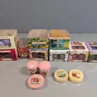 Sale Photo Thumbnail #122: Collection of Yankee Candle and Village Candle products, including boxed scented tea lights, small jar candles, votives, and wax melts in various floral and fruity scents.