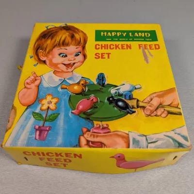 Sale Photo Thumbnail #193: Vintage Happy Land wooden Chicken Feed Set game in its original colorful box. Shows some edge wear and light surface tears on the lid.