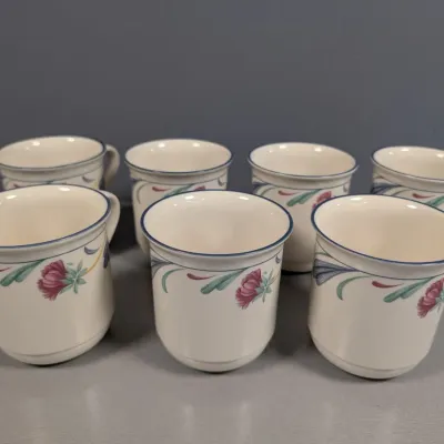 Sale Photo Thumbnail #125: Set of seven vintage Pfaltzgraff cream ceramic mugs featuring a floral design with blue rims.