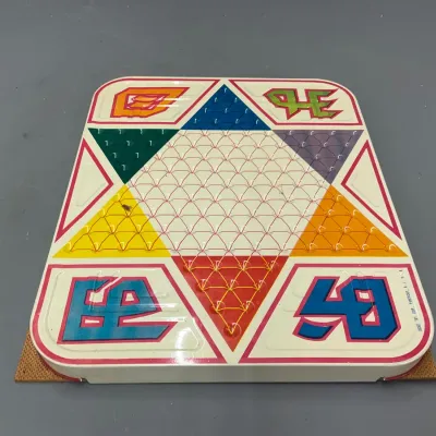 Sale Photo Thumbnail #235: Vintage tin lithograph Chinese Checkers game board by Tucker Toy Corp, featuring colorful geometric graphics and indented marble slots.