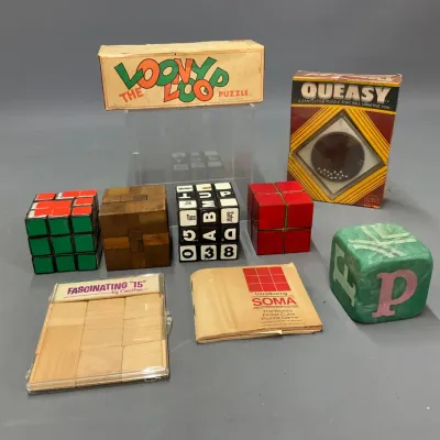 Sale Photo Thumbnail #401: Collection of vintage 1970s and 1980s mechanical brain teaser puzzles, including Rubik's-style cubes, wooden Soma puzzle elements, 'The Loony Loop', and 'Queasy'.