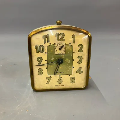 Sale Photo Thumbnail #233: Vintage Gilbert wind-up alarm clock with brass trim, featuring green stylized numerals and a secondary alarm dial.