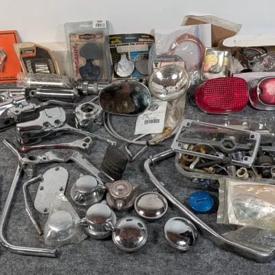 Sale Photo Thumbnail #89: Large assortment of vintage motorcycle parts and accessories, including chrome levers, tail light lenses, mirrors, hardware, and packaged components.