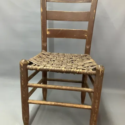 Sale Photo Thumbnail #102: Antique ladder-back wooden dining chair featuring a woven splint seat and visible distressed finish.