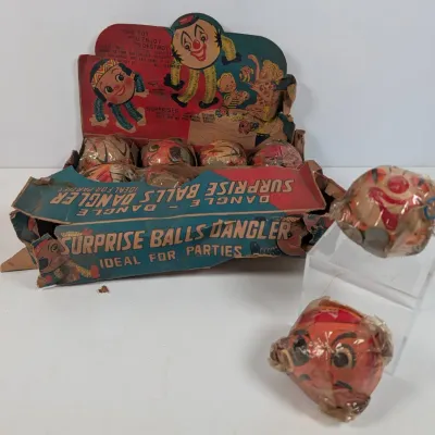 Sale Photo Thumbnail #340: Vintage 'Surprise Balls Dangler' store display box with original crepe paper wrapped novelty toys showing significant wear and tearing.