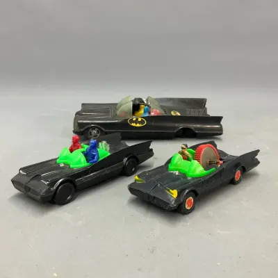 Sale Photo Thumbnail #299: Trio of vintage plastic Batmobile toys, including friction-powered and sparkler models, showing play wear.