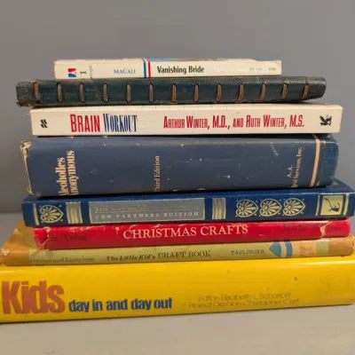 Sale Photo Thumbnail #23: Stack of vintage non-fiction and craft books, including a third edition hardbound copy of Alcoholics Anonymous and a leather-bound spiral notebook.