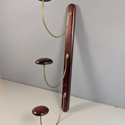 Sale Photo Thumbnail #156: Vintage Italian mid-century modern wall-mounted hat and coat rack with three brass curved arms, dark mahogany wooden mounts, and circular rests.