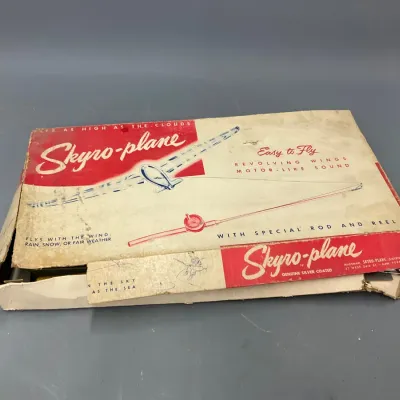 Sale Photo Thumbnail #296: Vintage Skyro-plane toy in its original box, featuring retro red and white graphic illustrations and showing significant wear and damage to the cardboard packaging.
