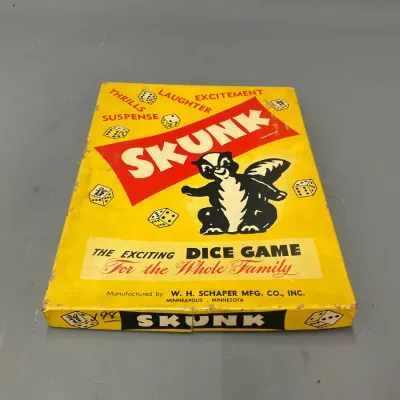 Sale Photo Thumbnail #223: Vintage Skunk dice game in original box by W. H. Schaper Mfg. Co., featuring bright yellow cover graphics with minor edge wear.