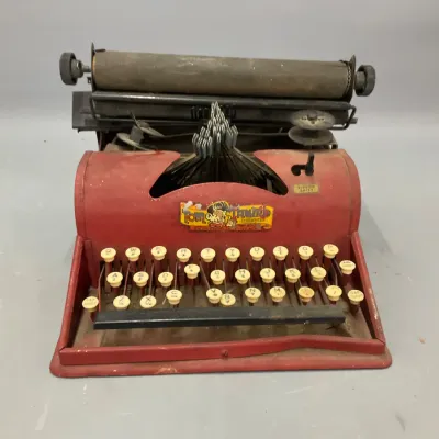 Sale Photo Thumbnail #215: Vintage Tom Thumb red tin toy typewriter, showing age-related wear and patination.