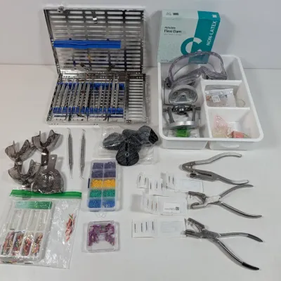 Sale Photo Thumbnail #36: Collection of dental and orthodontic tools and supplies, including a metal sterilizing cassette with instruments, impression trays, dental dam supplies, and various pliers.