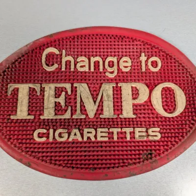 Sale Photo Thumbnail #319: Vintage red rubber advertising change mat for Tempo Cigarettes, featuring raised lettering and a textured nubbed surface.